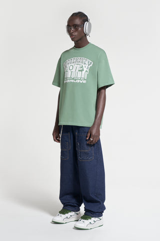 Model mit grünem Streetwear T-Shirt und Baggy Jeans für das perfekte Outfit.
